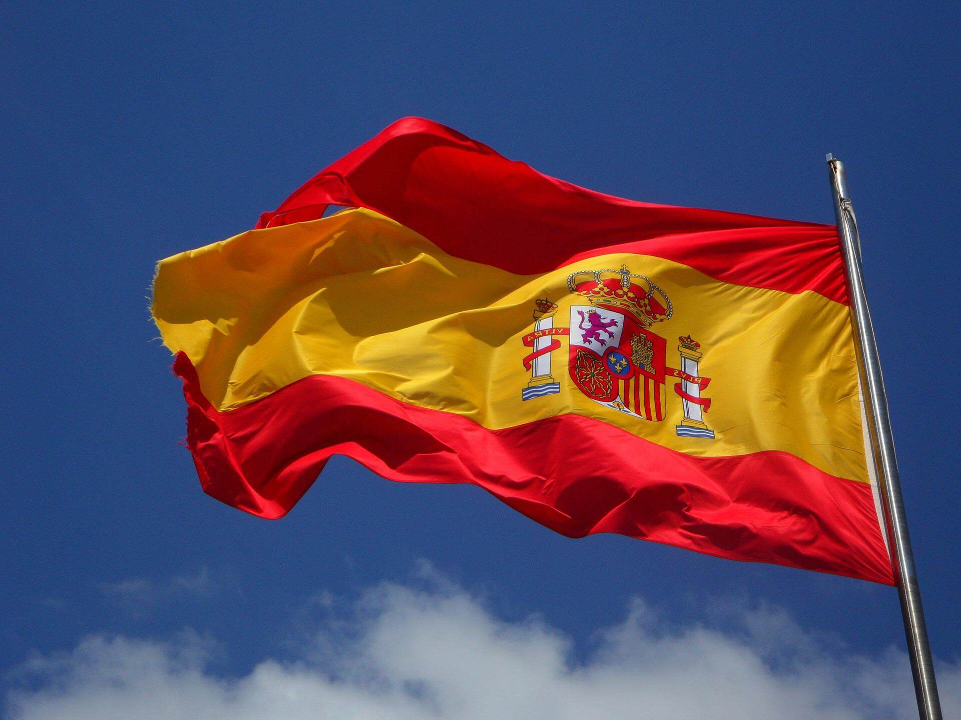 Spanish flag on mast against a blue sky backdrop
