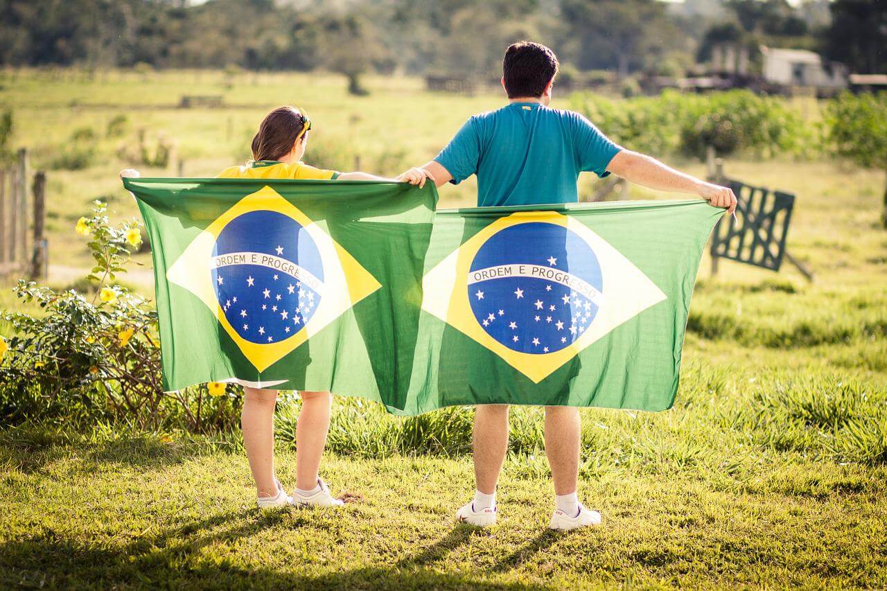 male and female holding a Brazil flag behind their back