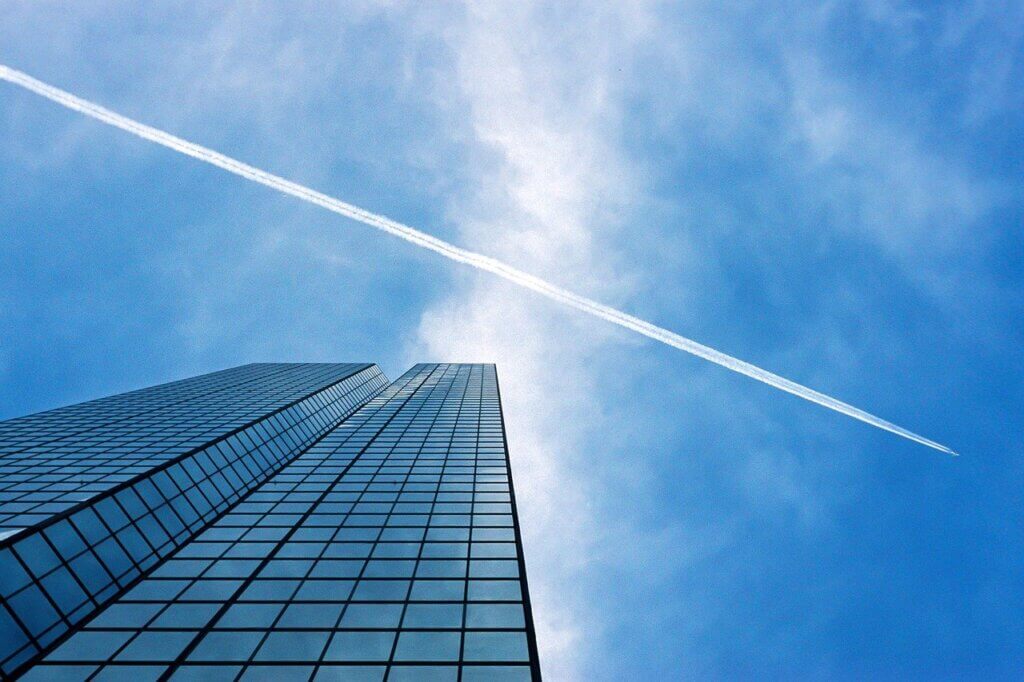 skyscraper and airplane against a blue sky 