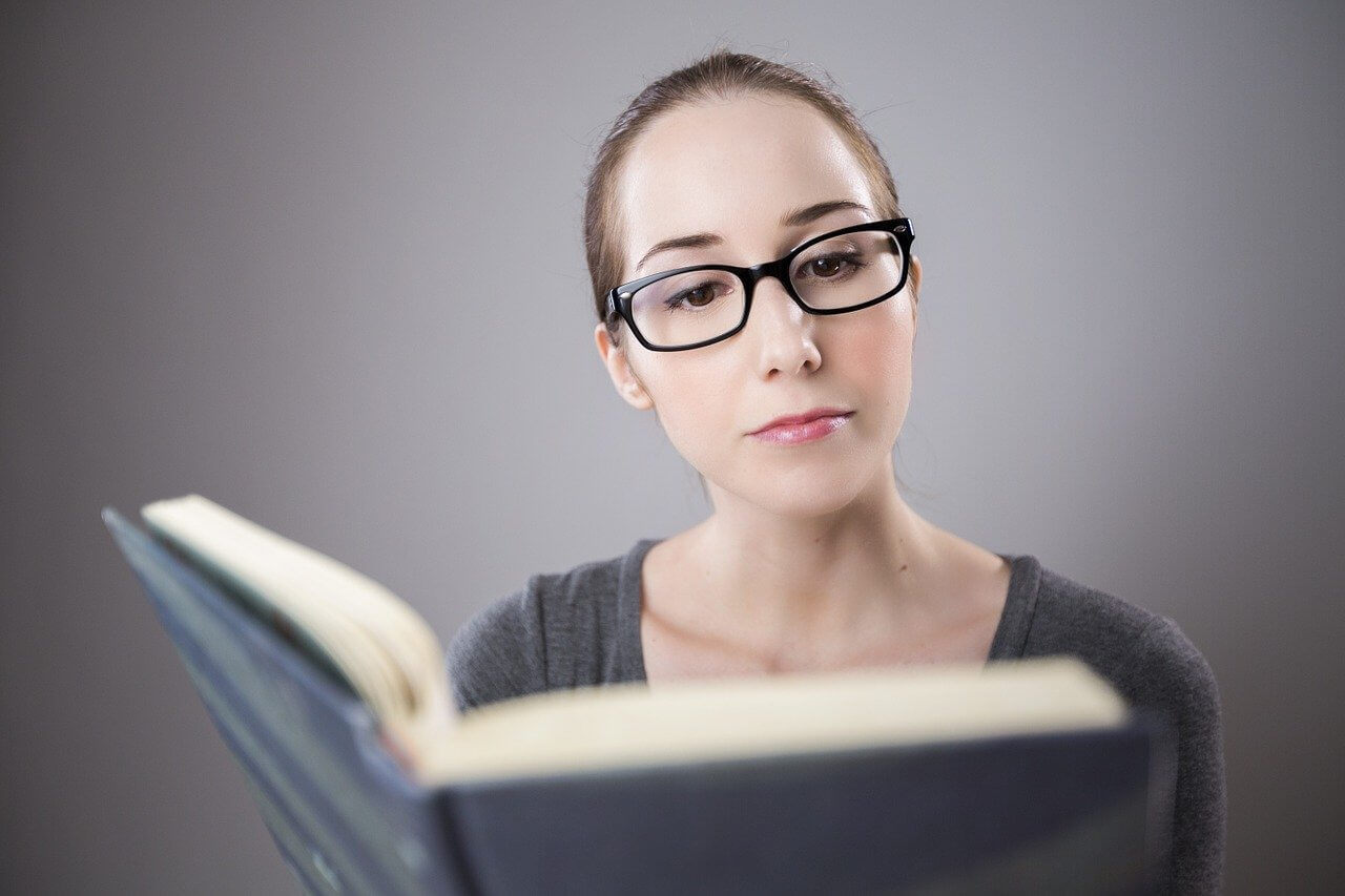woman with glasses reading a book