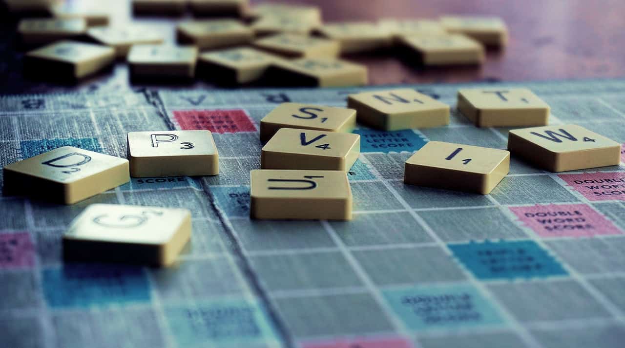 Scrabble tiles scattered on a chequered board.