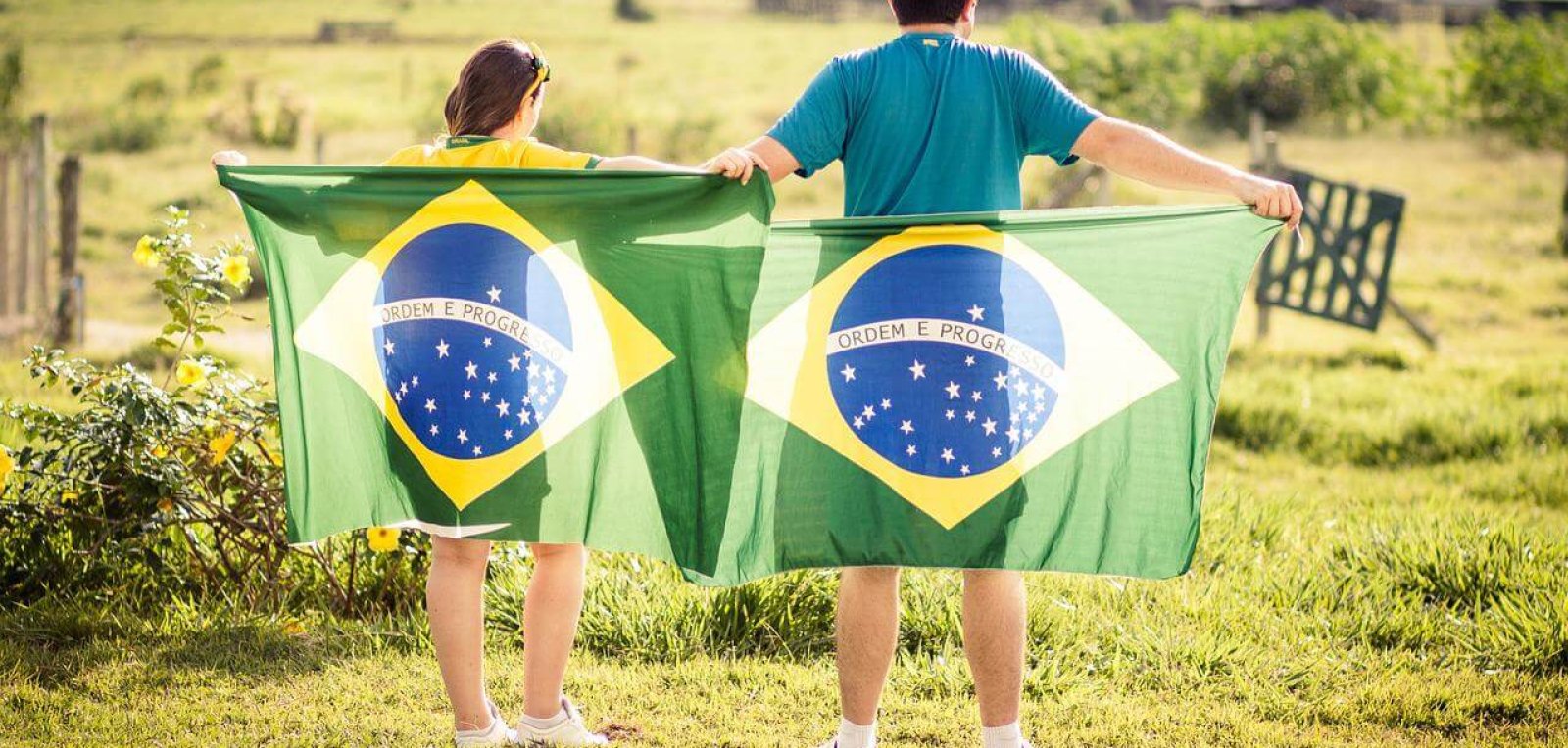male and female holding a Brazil flag behind their back