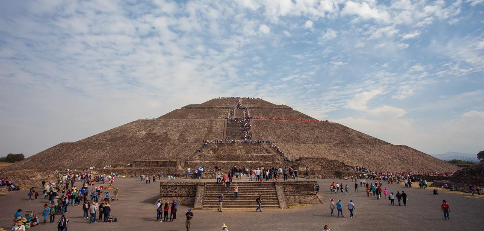 A pyramid in Teotihuacan visited by many tourists on a sunny day