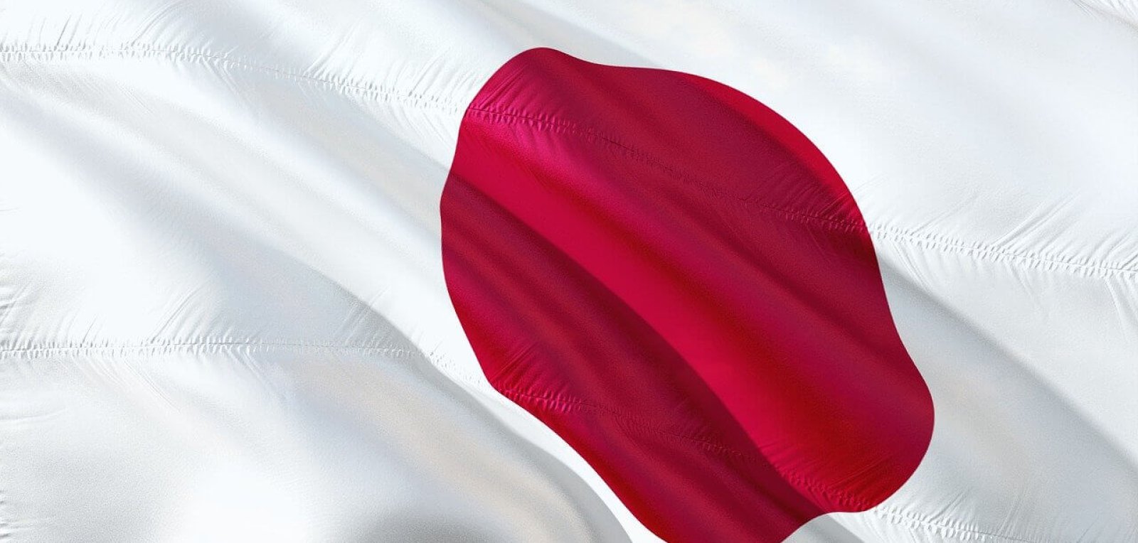 close-up shot of the flag of Japan against a blue sky backdrop